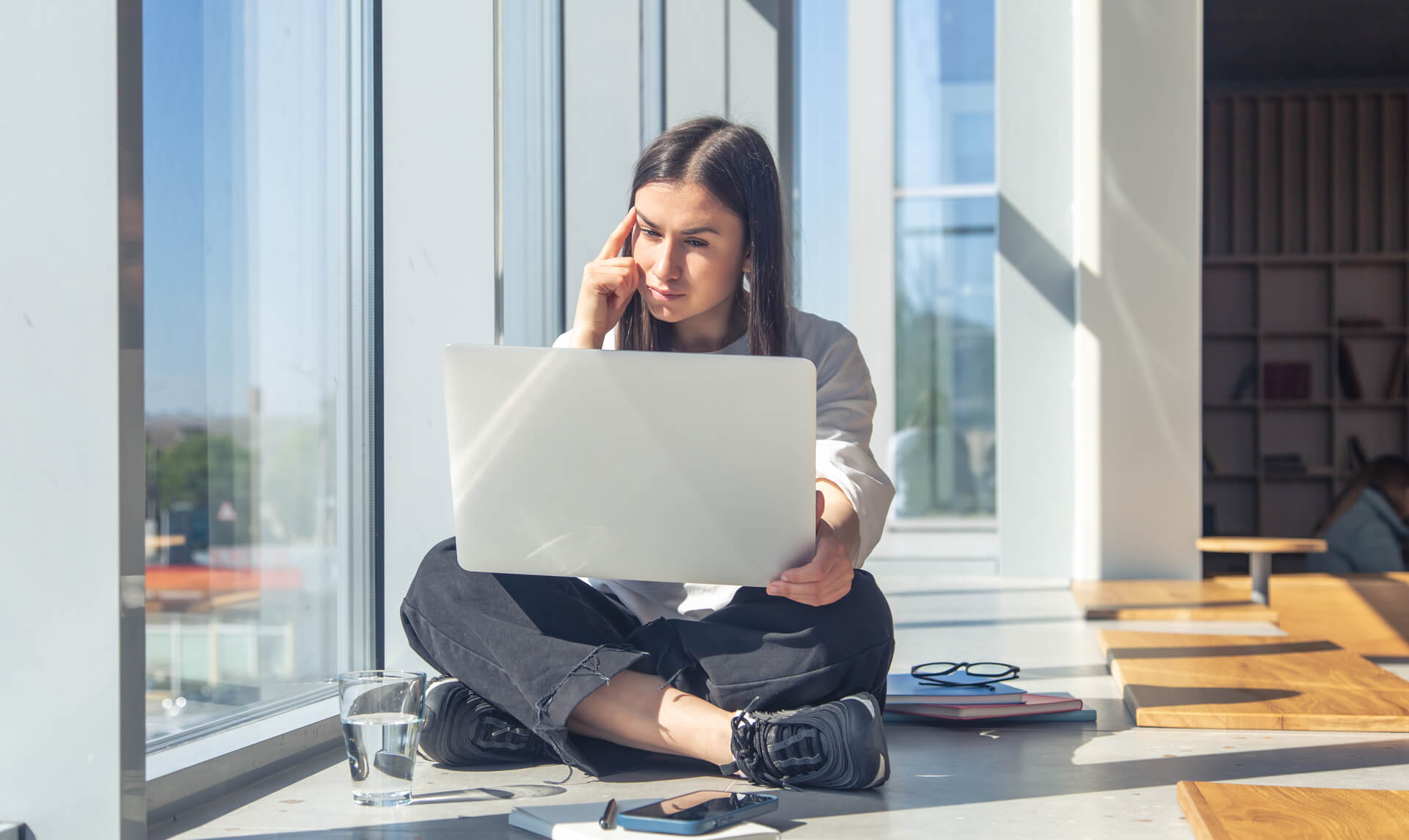 thoughtful-young-woman-front-laptop-screen-office-by-window (1) (1)